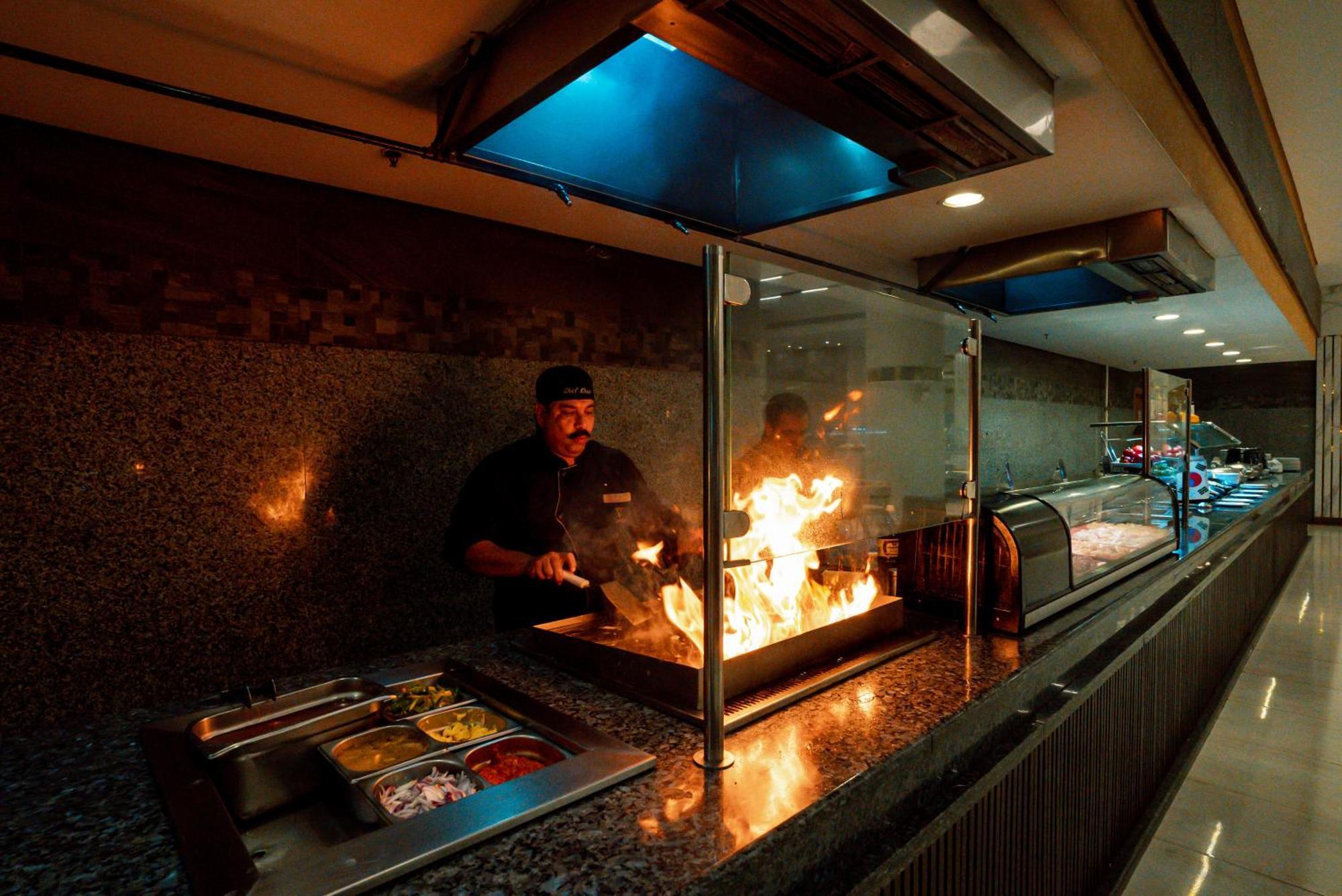The V Luxury Resort Sahl Hasheesh Hurgada Dış mekan fotoğraf A chef cooking with a flaming torch